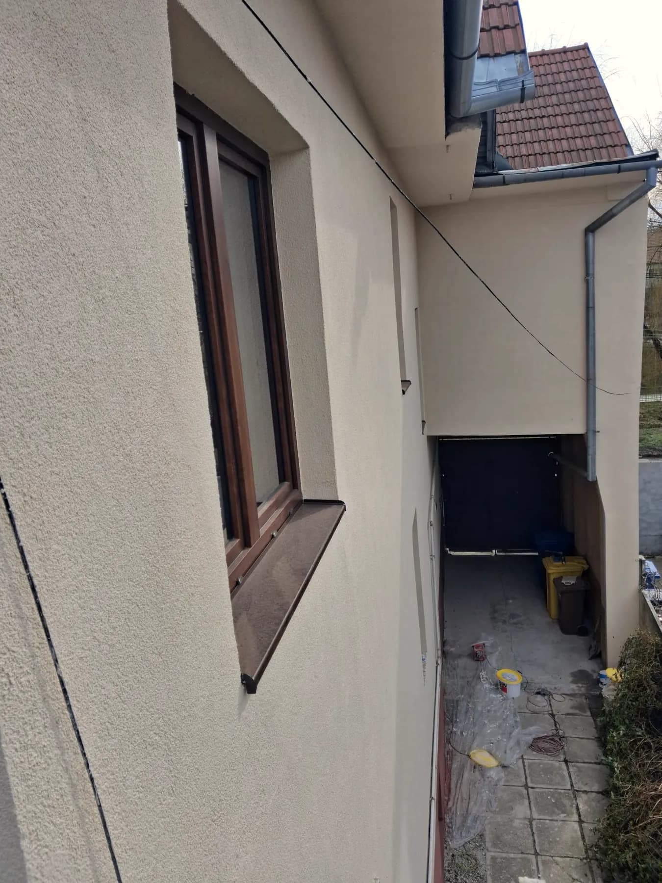 Fațadă renovată cu tencuială decorativă și glaf maro la fereastră