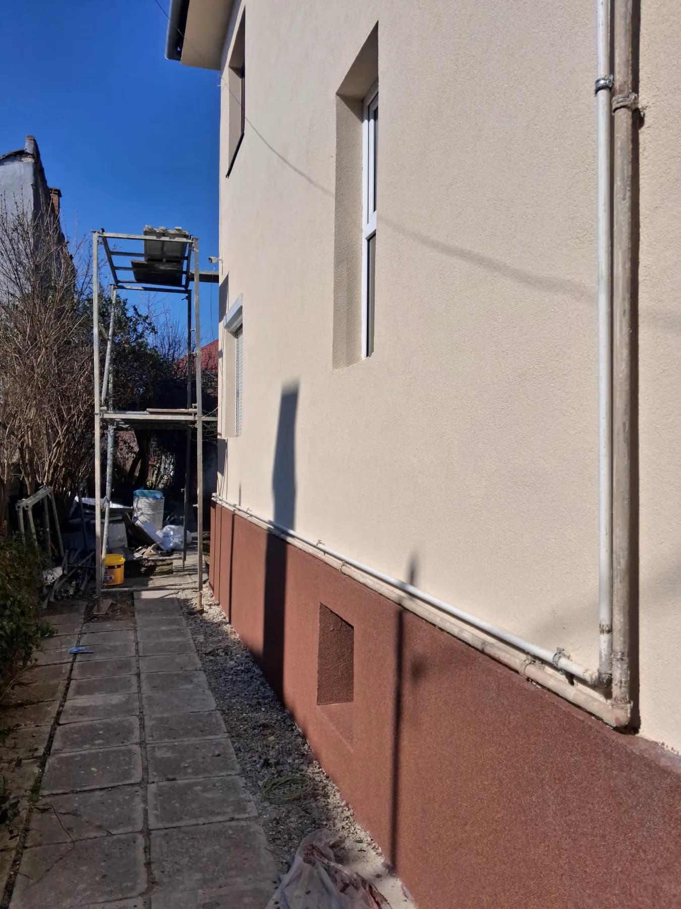 Casă locuită cu tencuială decorativă bej și soclu teracotă